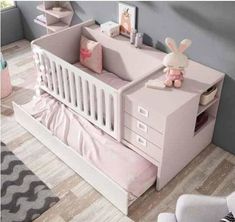 a baby's room with a pink crib, dresser and stuffed animal on the floor