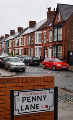 there is a sign that says penny lane in front of some cars parked on the street