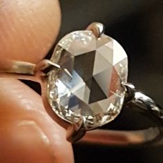 a close up of a person holding a ring with an oval cut diamond on it