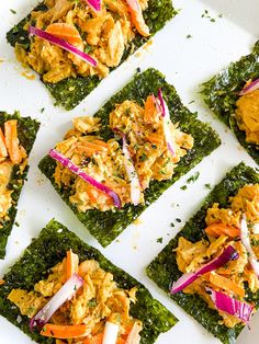 several square pieces of food on top of a white plate with red onions and carrots