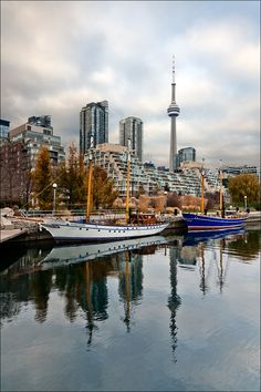 two boats are docked in the water near some tall buildings and a sky scraper