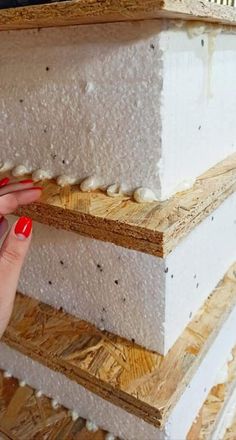 a woman's hand is touching the edge of a stack of wood planks