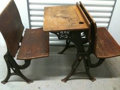 an old school desk and two chairs are sitting in front of a wall with shutters