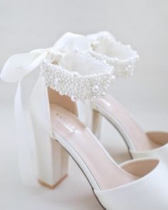 a pair of white shoes with pearls on them