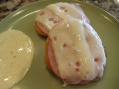 a green plate topped with two donuts covered in icing next to a bowl of sauce