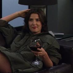 a woman sitting on a couch holding a glass of wine