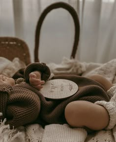 a baby doll laying on top of a bed next to a brown purse and white blanket