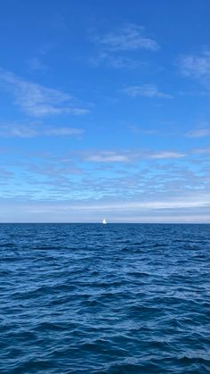 an ocean view with a boat in the distance under a blue sky and white clouds