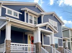 a row of houses with blue siding and white balconies on the front porch