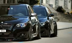 two black cars are parked on the street