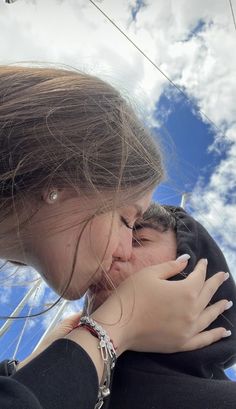 a woman is kissing her baby on the cheek while she looks up into the sky