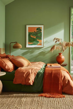 a bedroom with green walls and orange linens on the bed, along with an area rug