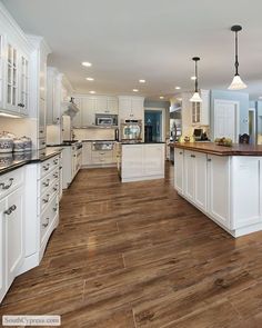 a large kitchen with wooden floors and white cabinets