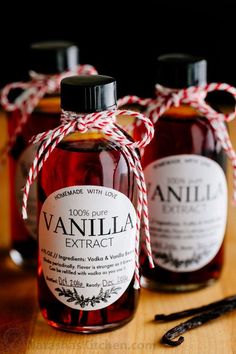 three bottles of vanilla syrup tied with twine on a wooden table next to cinnamon sticks