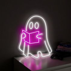 a neon sign with a ghost reading a book on it's side in the dark