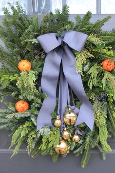 a wreath with bells and greenery on the front door is adorned with blue ribbon