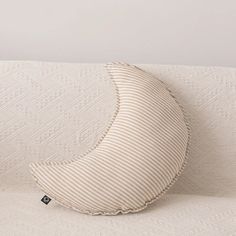 a banana shaped pillow sitting on top of a white couch cushion in front of a wall