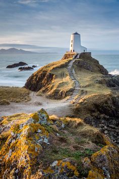 a light house on top of a hill next to the ocean with steps leading up to it