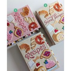 three embroidered book covers with words and pictures on them, each containing different types of food