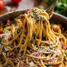 a fork full of spaghetti with tomatoes and parmesan cheese