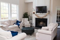 a living room filled with furniture and a flat screen tv mounted on the wall above a fire place