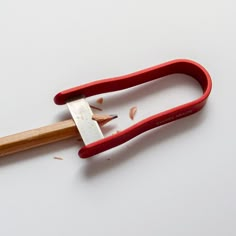 a pair of red handled scissors with wood shavings