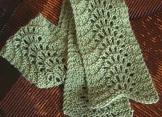 two green crocheted ties laying on top of a brown cloth covered in yarn