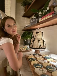 a woman standing in front of a table with cupcakes and cakes on it