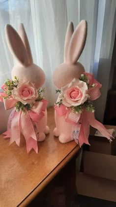 two stuffed rabbits with pink flowers on them sitting on a table next to a window