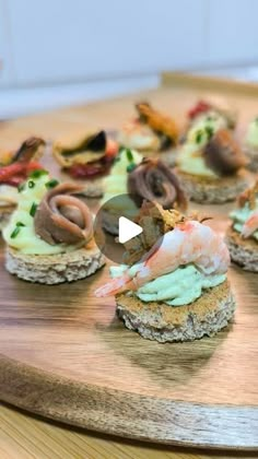 a wooden board topped with mini sandwiches covered in toppings