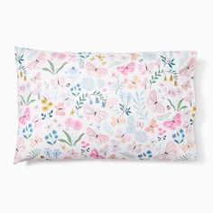 a pink and blue floral pillow with butterflies on the front, sitting on a white surface