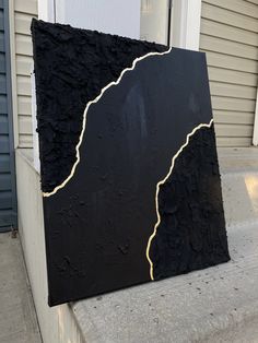 a black and gold piece of art sitting on top of a cement step next to a door