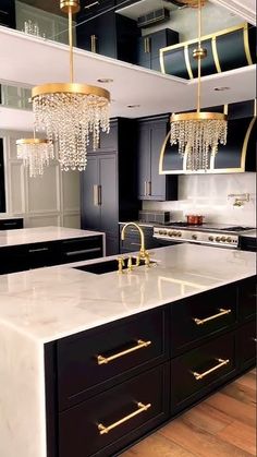 a kitchen with black cabinets and white counter tops, gold accents on the chandelier