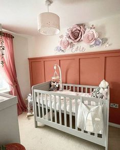 a baby's room is decorated with pink and white flowers on the wall, along with a crib