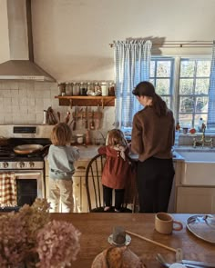 a woman and two children are in the kitchen