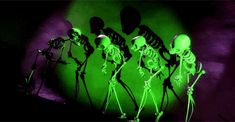 three skeletons standing in front of a green light