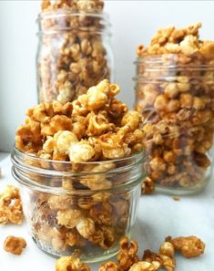 three glass jars filled with nuts on top of a table