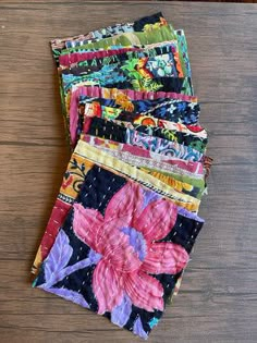 four pieces of colorful fabric sitting on top of a wooden table next to each other