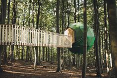 a tree house in the woods with a green umbrella hanging from it's roof