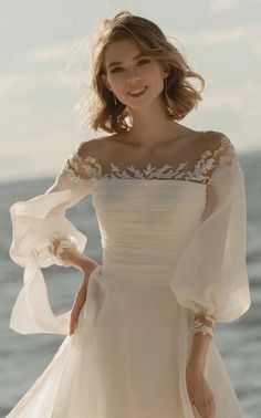 a woman in a white dress standing on the beach