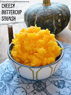 a bowl filled with mashed butter on top of a table next to pumpkins