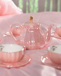 a pink tea set sitting on top of a bed