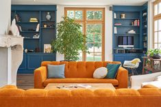 a living room with orange couches and blue bookshelves on the wall behind them