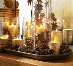 candles and pine cones are arranged in glass vases on a table with the words justin written above them