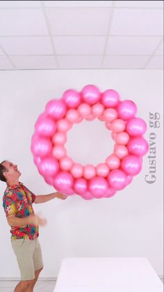 a woman is holding a large balloon in the shape of a letter o while standing next to a bed