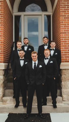 a group of men in tuxedos posing for a photo on the front steps of a building