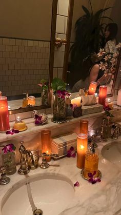 a bathroom sink with candles and flowers on it