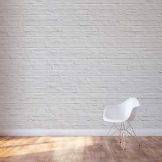 a white chair sitting on top of a hard wood floor next to a brick wall