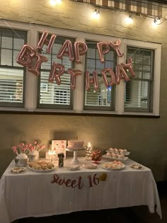 a birthday party with balloons and food on a table in front of a window that says happy birthday sweet 16