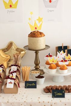 a table topped with cakes and cupcakes covered in frosting next to other desserts